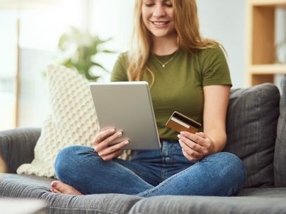Eine Frau macht auf einer Couch Online-Banking